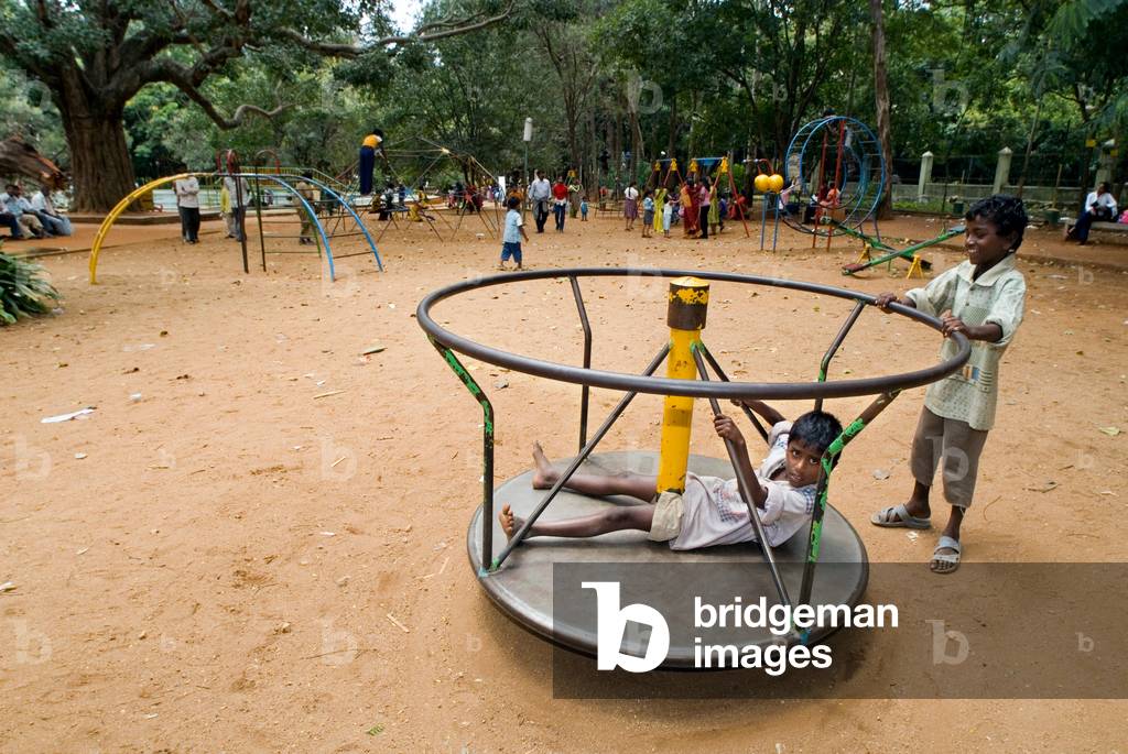 Boys playing on a roundabout in the children's amusement park, Bal Bhavan, Cubbon Park, Bangalore, Karnataka, India
