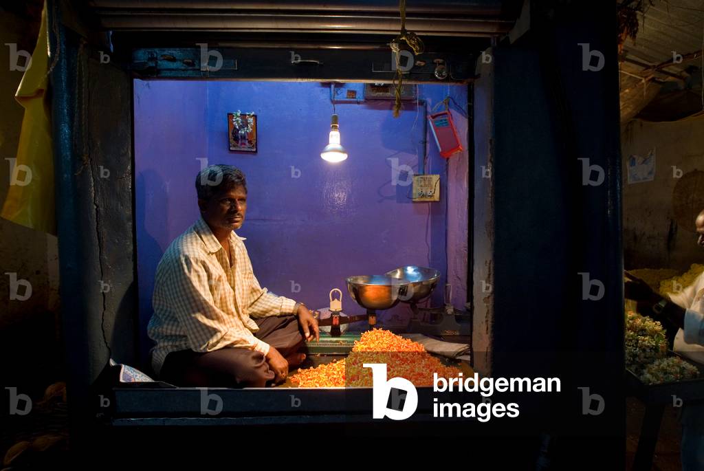 Flower seller in nighttime city market (photo)