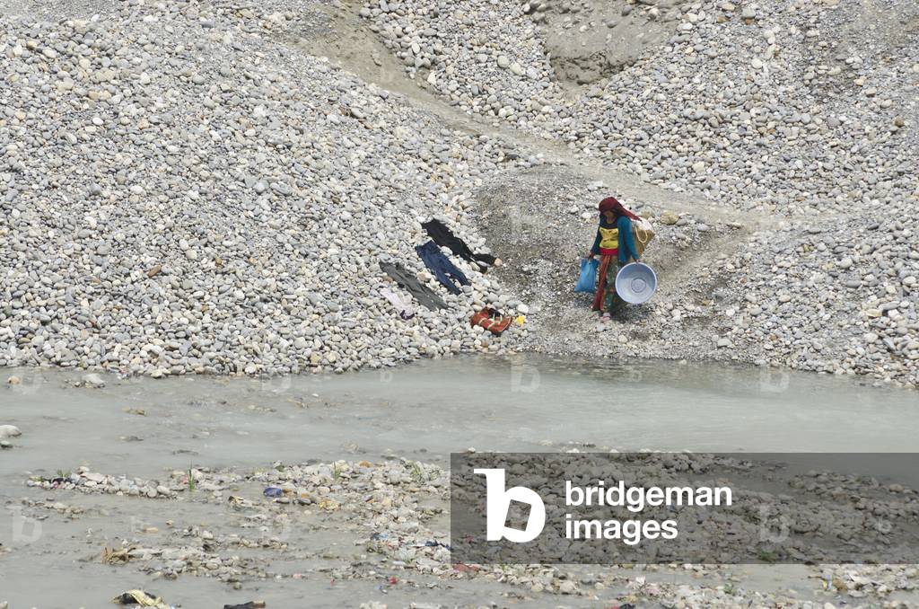 Nepali woman washing clothes in stony river valley, 
Seti Gandaki River Gorge, Pokhara, Nepal (photo)