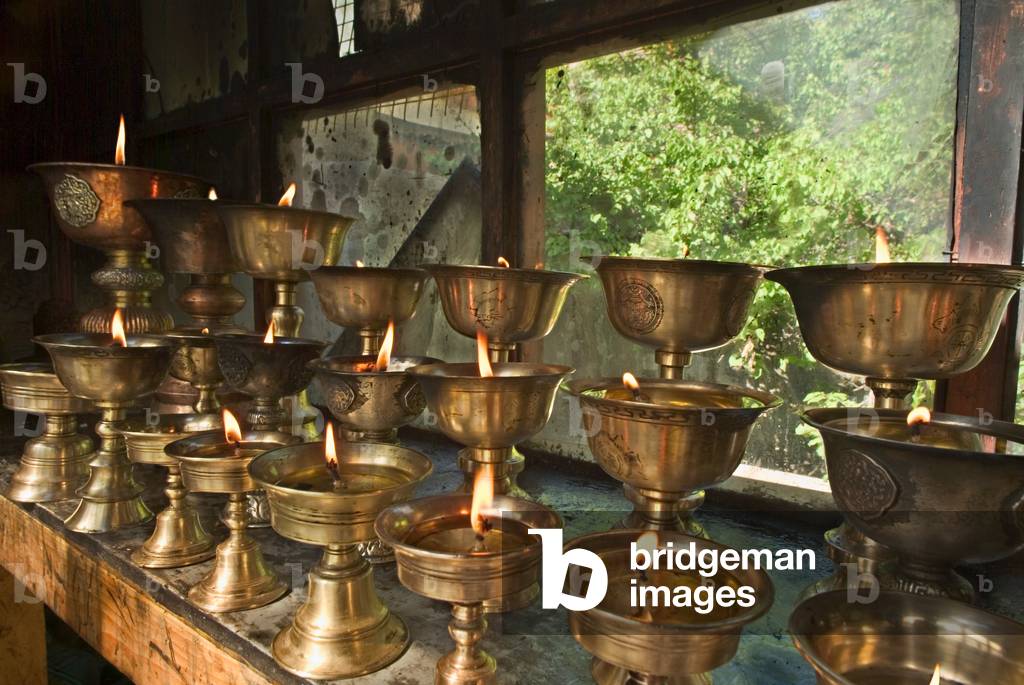 Tibetan Buddhism (Tantric Buddhism, Vajrayana): Butterlamps in monastery window overlooking wild garden Alchi Gompa, Ladakh, Himalayas, Jammu and Kashmir, India (photo)