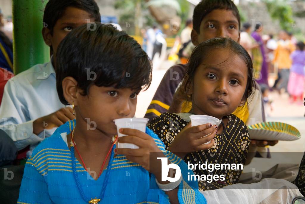 Children drinking water from plastic cups in Bal Bhavan children's park inside Cubbon Park Bangalore, Karnataka, India
