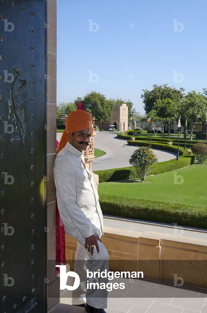 Palace guard standing in doorway looking onto lawns and drive at Umaid Bhawan Palace,
Jodhpur, Rajasthan, India (photo)