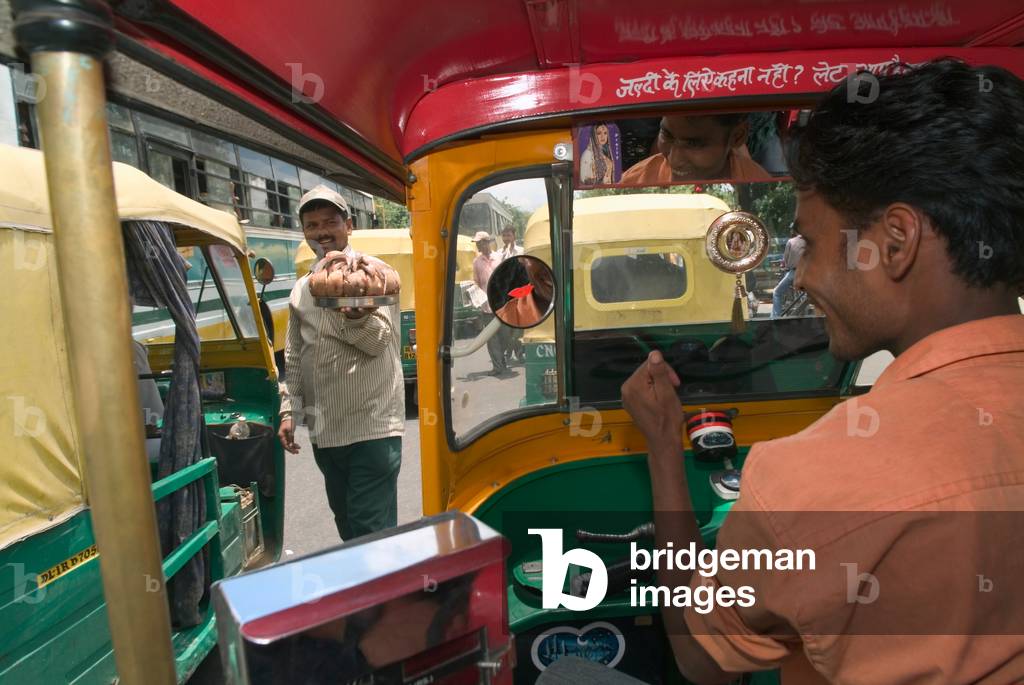 Indian street trader/food seller approaching driver in autorickshaw Delhi, India (photo)
