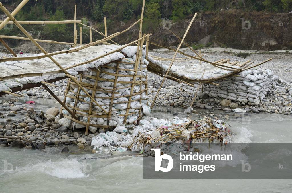 Temporary dry-season river footbridge made from sandbags & bamboo, 
washed-up rubbish/garbage, 
Seti Gandaki River Gorge, Pokhara, Nepal (photo)