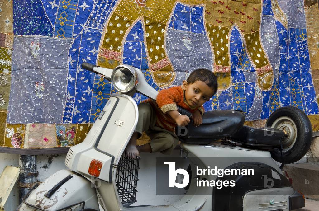 Toddler climbing on parked motor scooter,
The Old Blue City, Jodhpur, Rajasthan, India (photo)