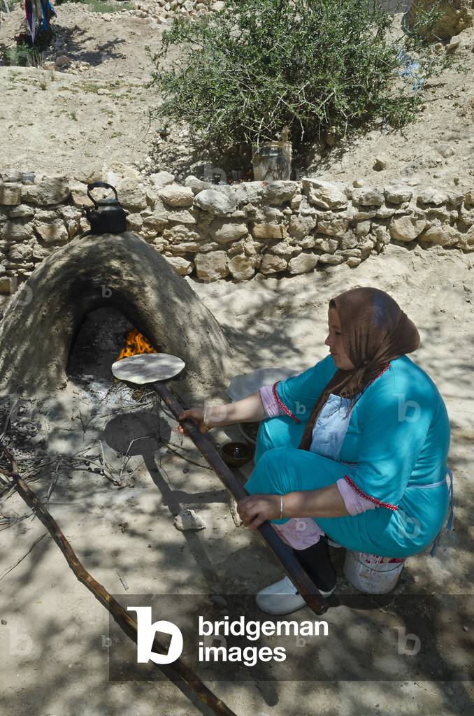 Berber  woman baking bread in outdoor clay oven in mountain village, Tazglimt, High Atlas Mountains, Taroudant Province, Morocco (photo)