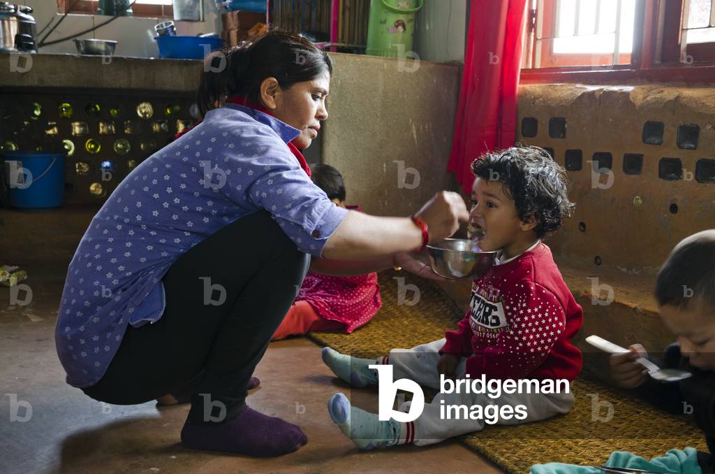 Nursery carer feeding child, Ankuran Education Centre, Kahare, Chalnakhel, Kathmandu Valley, Nepal (photo)