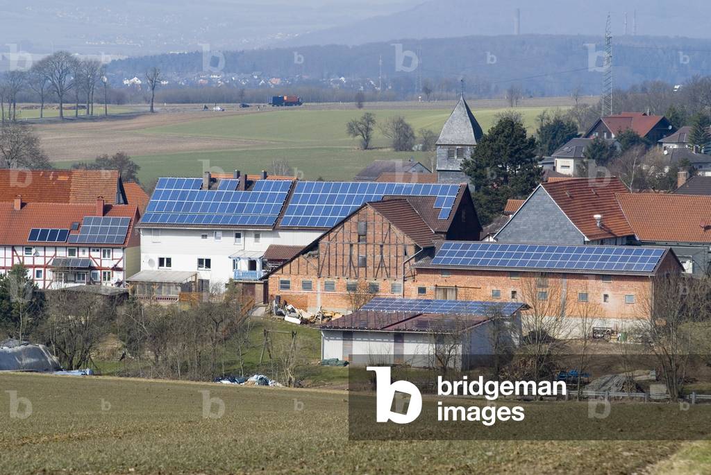 Solar PV panels on roofs of houses and barns in old timber-framed farming village in rural landscape, Wollrode, Hesse, Germany (photo)