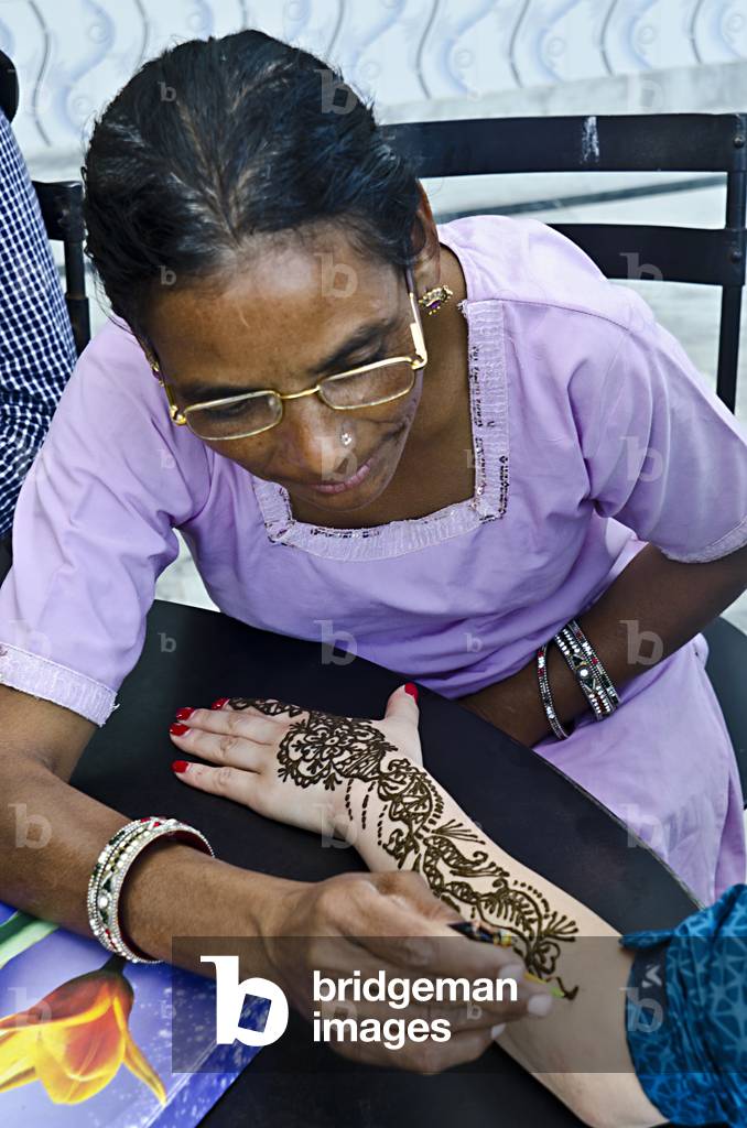 Woman applying mehndi to arm of other woman,
Jodhpur, Rajasthan, India (photo)