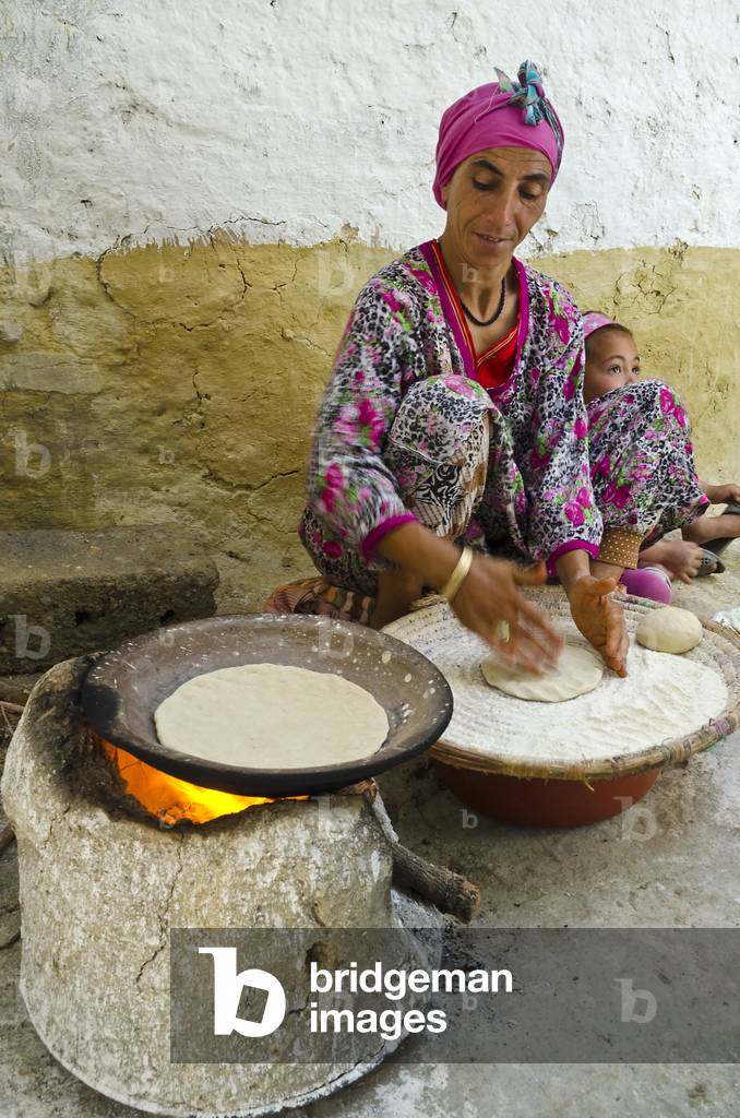 Berber woman  baking bread on wood-fired stove, Riad, High Atlas Mountains, Taroudant Province, Morocco (photo)