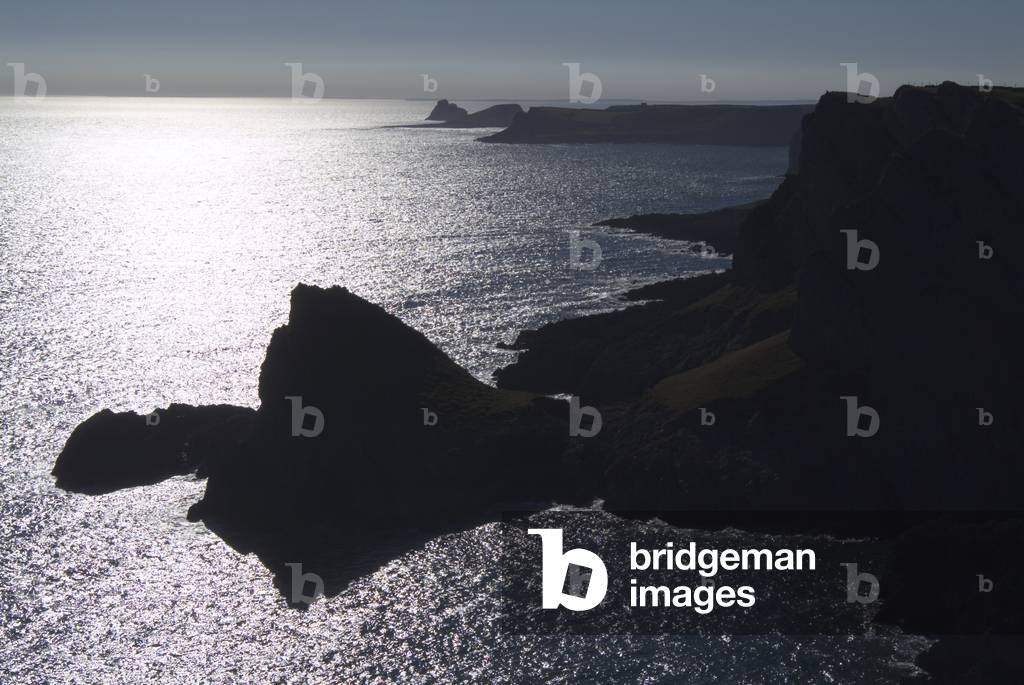 Silhouetted coastline from Foxhole Slade to Worms Head, the 'Knave' in the foreground, South Gower National Nature Reserve, Gower, South Wales, United Kingdom (photo)