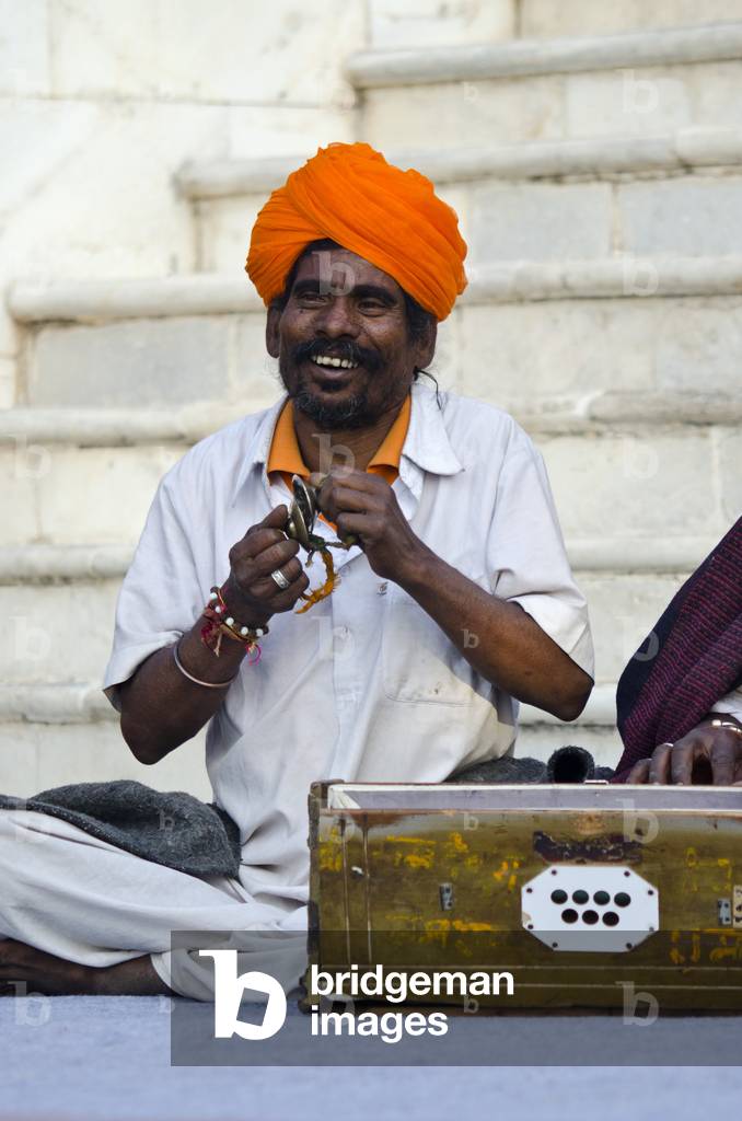Western Rajasthani red-turbaned traditional musician chanting and playing pair of small hand cymbals,
Jodhpur, Rajasthan, India (photo)