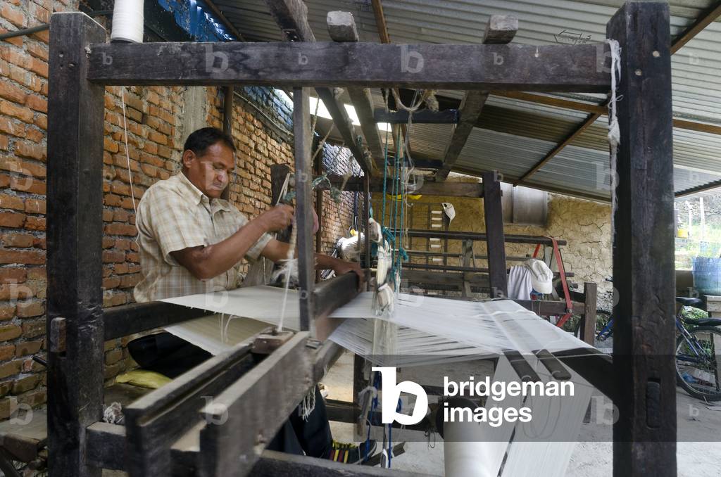 Nepali traditional weaver operating a handloom (foot-treadle floor loom), Kahare, Chalnakhel, Kathmandu Valley, Nepal (photo)