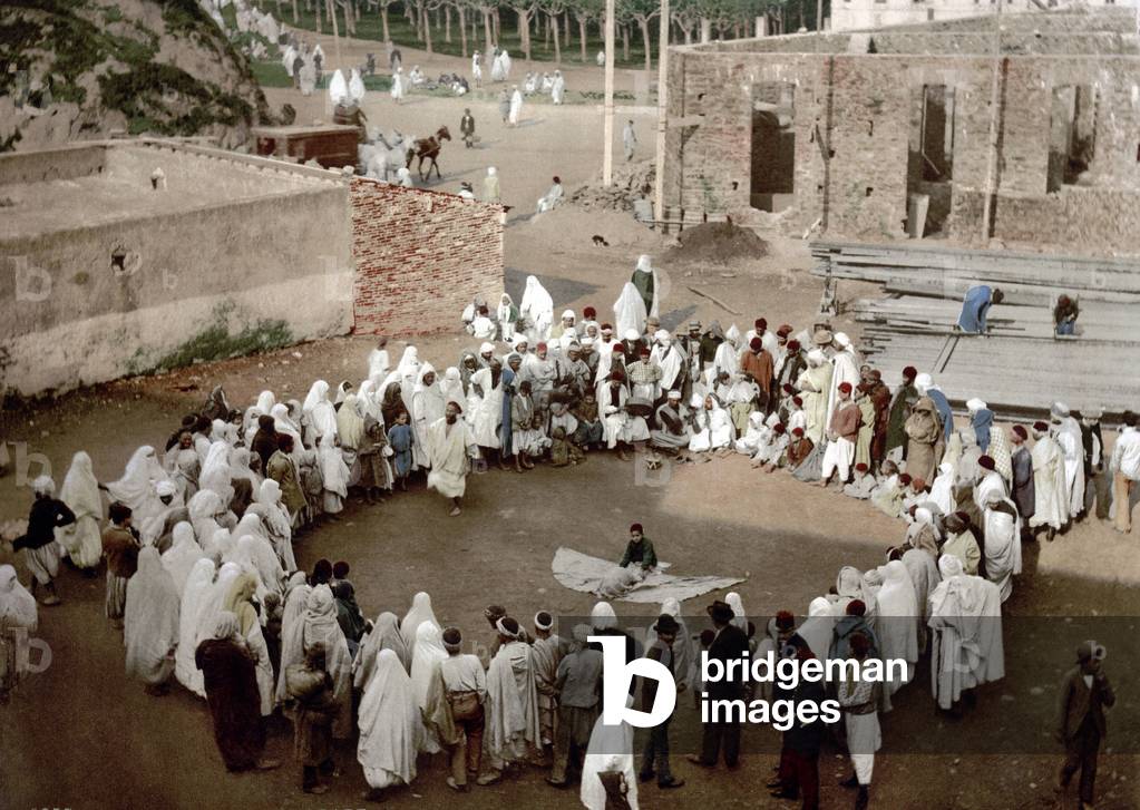 A crowd gathered around a street performer, Algiers, c. 1899 (photochrome)