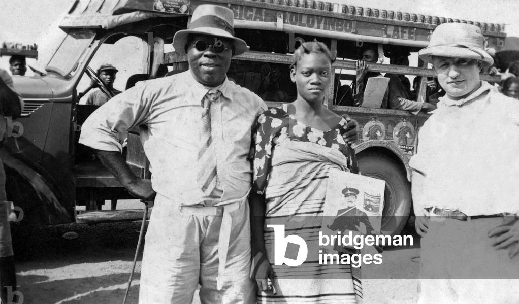 Lagos, Nigeria, 30's : ad campaign for Bandmaster cigarettes imported by the CFAO (Compagnie Francaise de l'Afrique Occidentale). On r : Andre Vidal (from the CFAO), on r : a local campaign director, c : a young African woman distributing samples of cigarettes