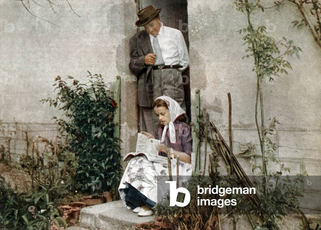 Jeanne Moreau with her father Anatole at home in Mazirat, France, reading Manufrance catalogue (weapons) c. 1948