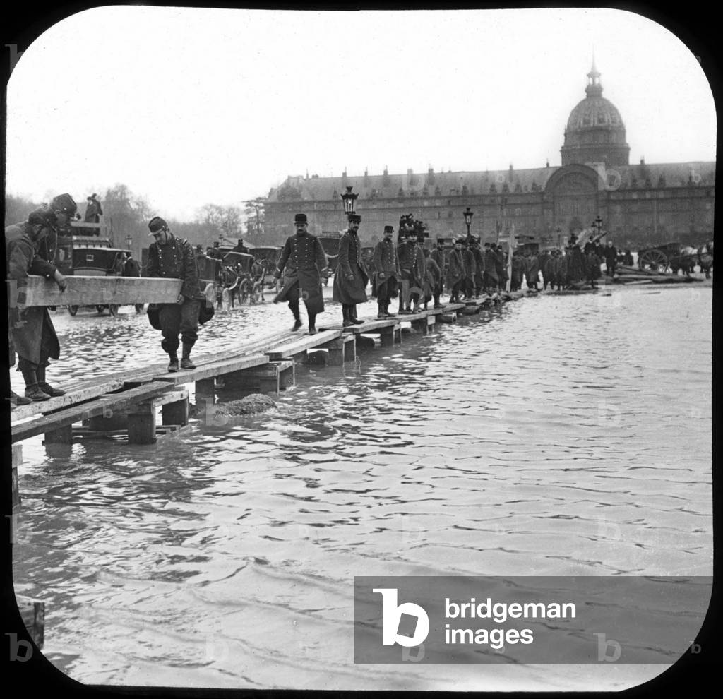 flood in Paris: soldiers build a passage on stilts, 1910 (b/w photo)