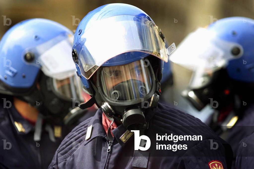 Image of Italian riot police wear gas masks as they stand guard