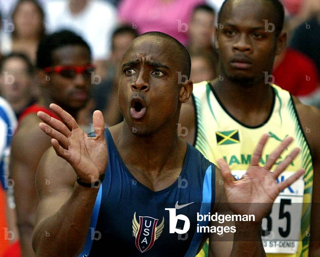 Image of U.S. sprinter Jon Drummond (C) reacts near Jamaica's Asafa Powell