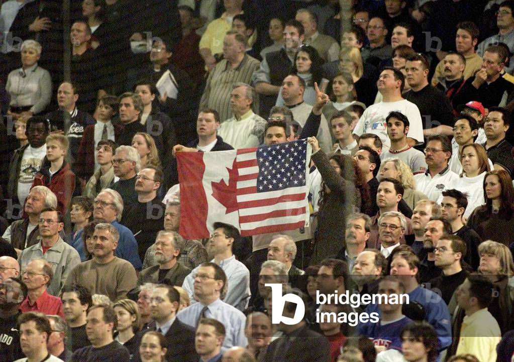 FANS WITH FLAG STAND FOR GOD BLESS AMERICA AT BLUE JAYS AND YANKEES
GAME, 2003-03-31 (photo)