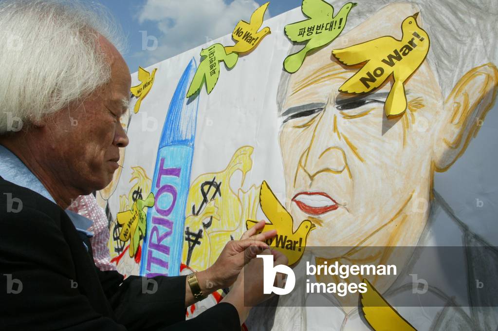 A SOUTH KOREAN PROTESTER ATTACHES AN ANTI-WAR BANNER TO A PICTURE OF US
PRESIDENT BUSH IN SEOUL, 2003-09-25 (p