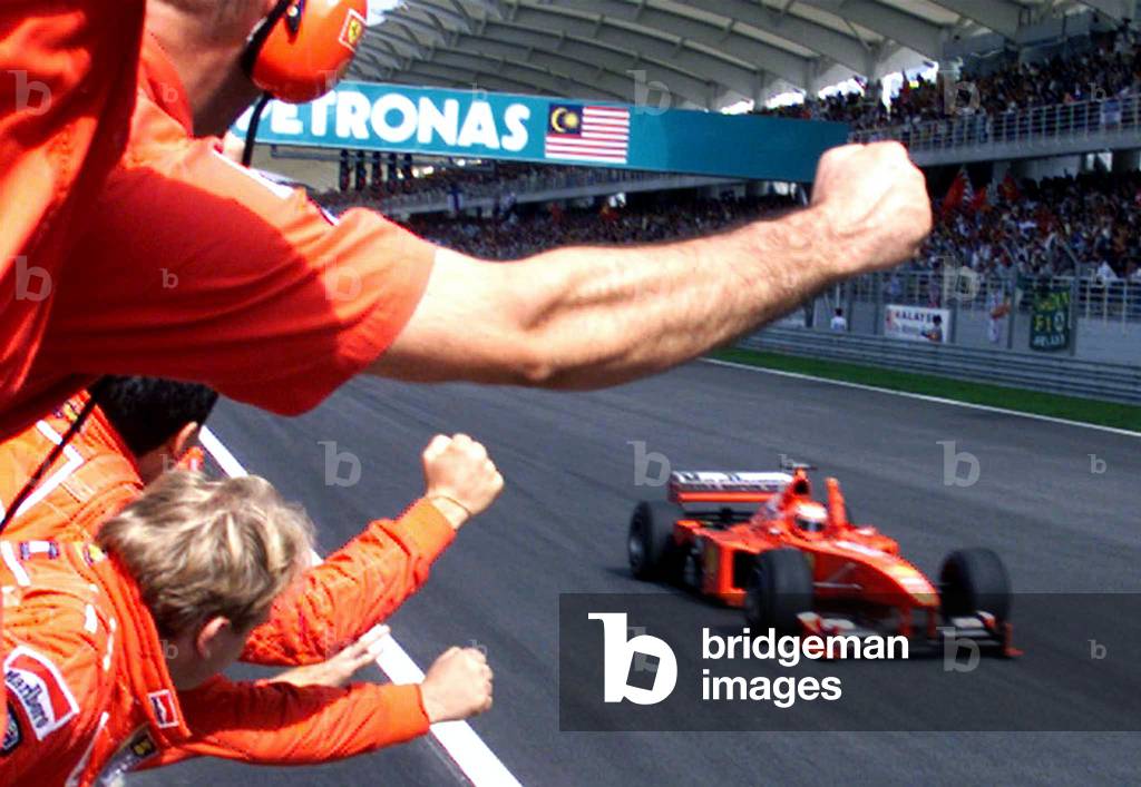 Image of Ferrari team members celebrate as race winner Eddie Irvine crosses