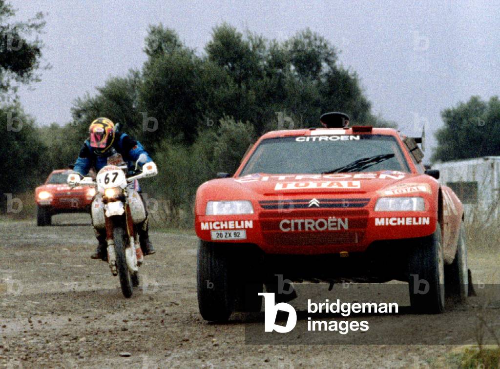 Timo Salonen of Finland passes a motorcycle fellow followed by countryman Ari Vatanen during the first stage o