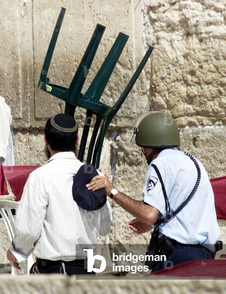 Image of JEWISH WORSHIPPER COVERS HEAD WITH A CHAIR AS ISRAELI POLICE