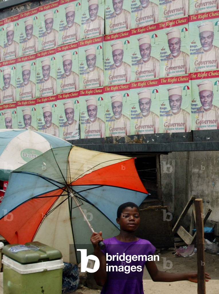 CHILD SELLS SWEETS UNDER CAMPAIGN POSTERS OF ELECTION CANDIDATES IN
LAGOS, 2003-04-10 (photo)