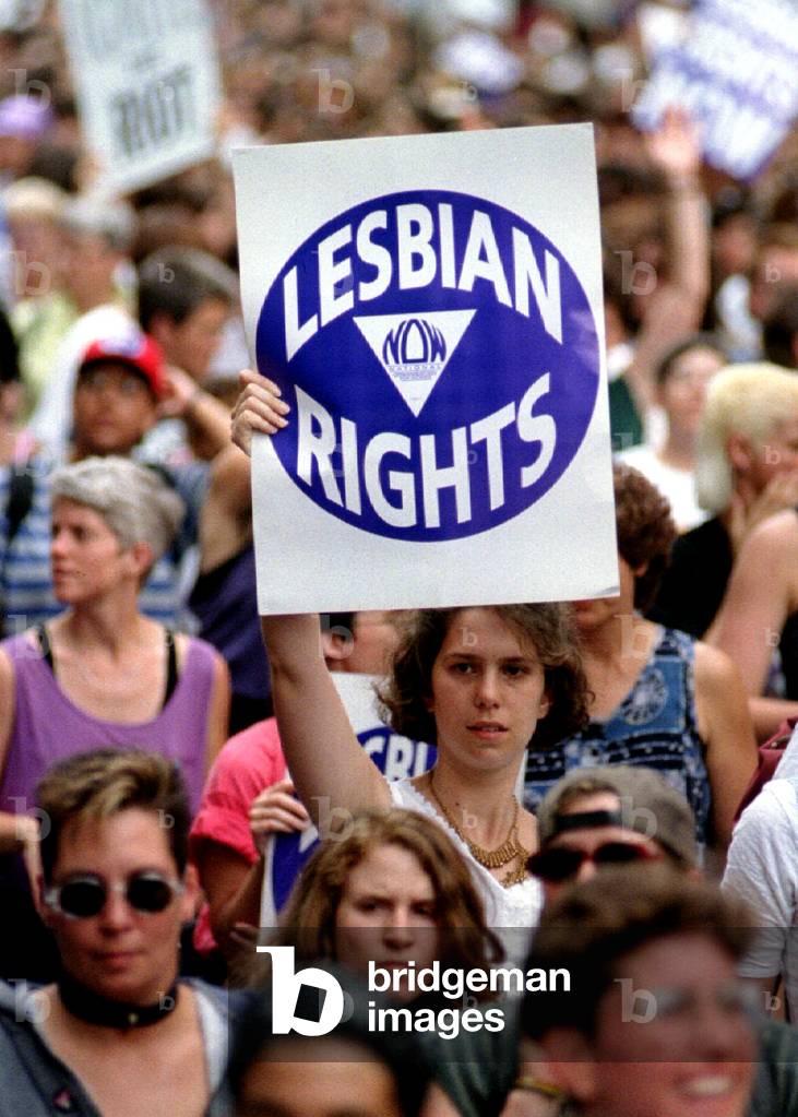 Image of A woman holds up a lesbian rights sign as she