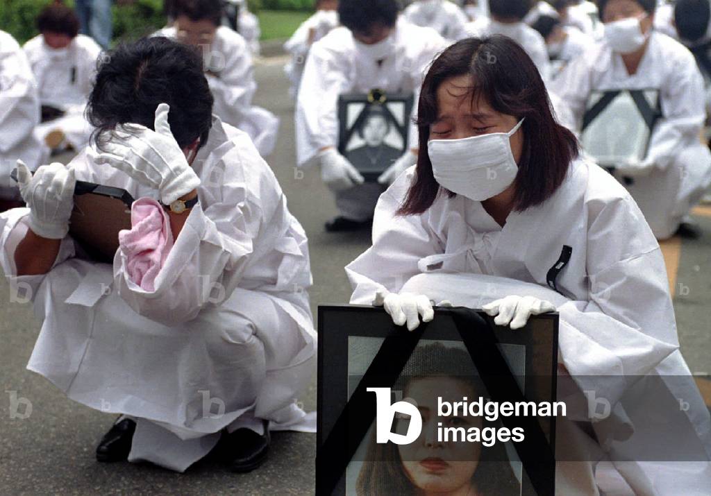Image of South Koreans wearing traditional Korean funeral white, hold