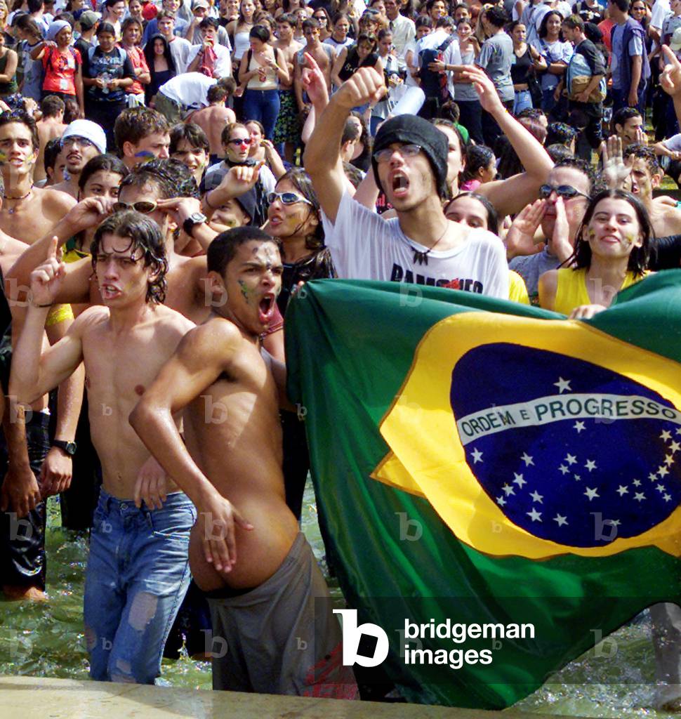 Image of Holding a Brazilian flag, student demonstrators shout anti ...