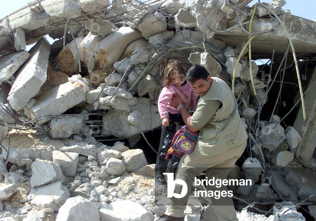 Image of A PALESTINIAN CARRIES A GIRL FROM THE RUBBLE OF A
