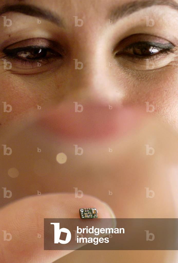 Mimi Farah holds through a magnifying glass the world's smallest microchip ever designed for a heari.., 1999 (