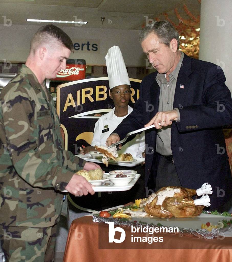 Image of U.S. President George W. Bush carves a turkey for members