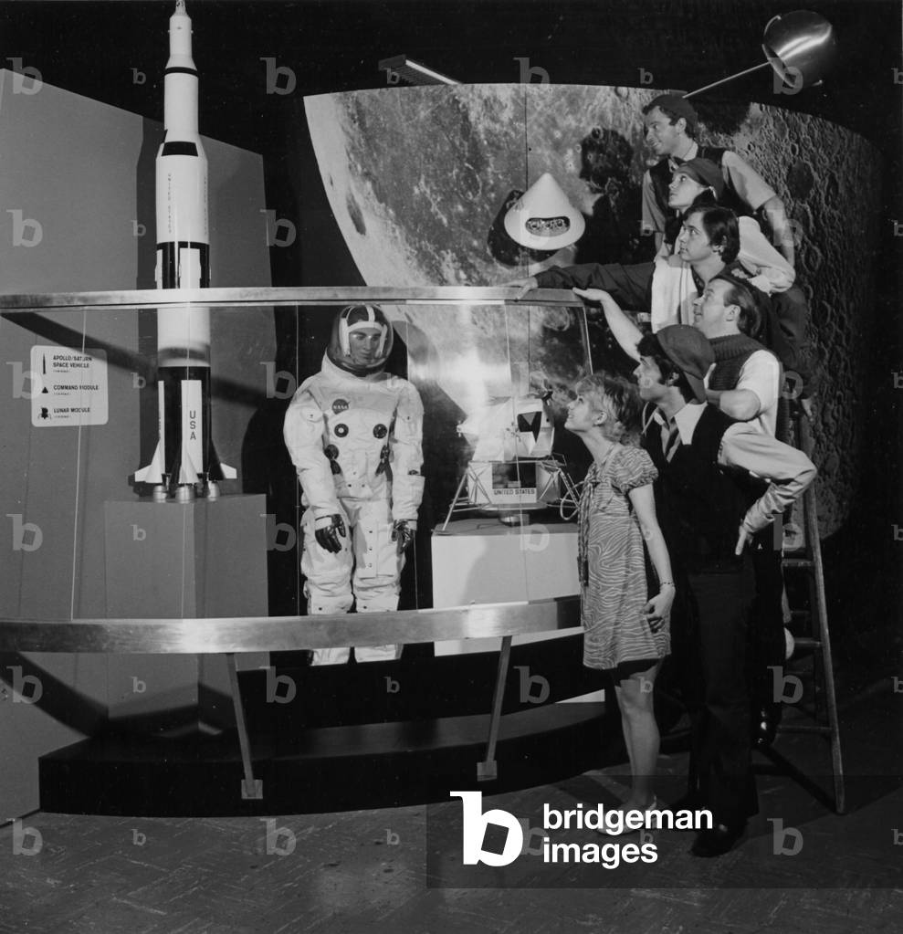 A Group Of People Pose On A Ladder In Front Of The NASA Apollo Exhibit