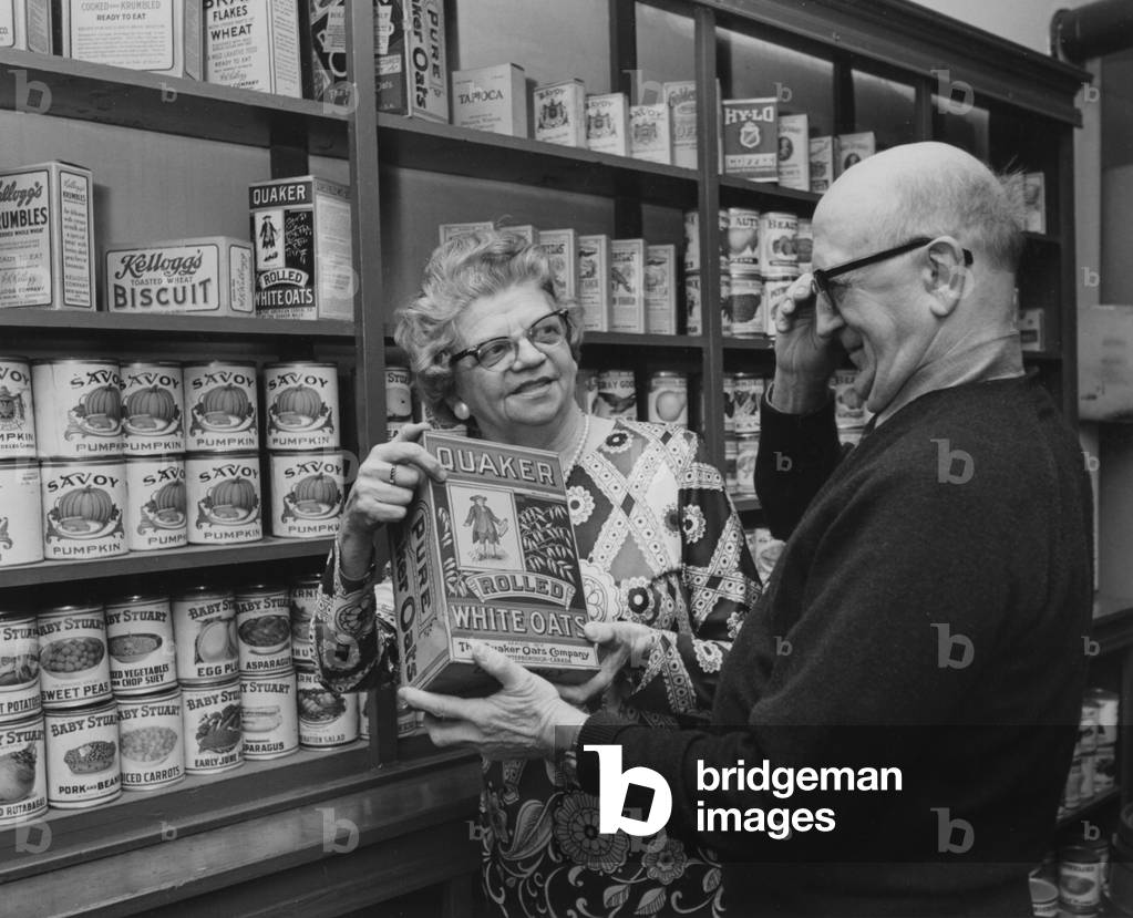 Two Seniors Looking At An Early Style Box Of Quaker Oats