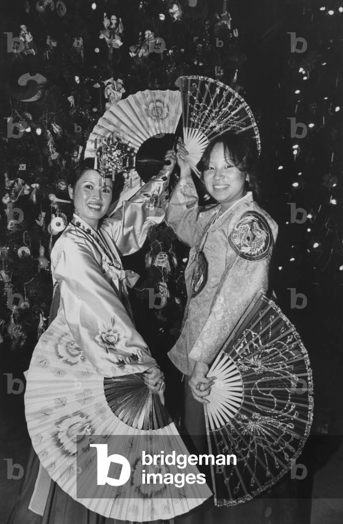 Two Korean Women With Fans Pose In Front Of The Korean Tree During The Annual Christmas Around The World Festival