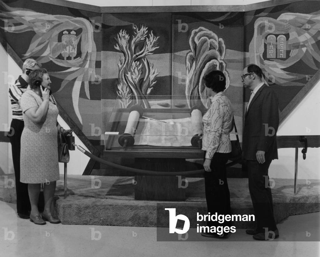 A Group Of People Viewing A Large Jewish Scroll On Display