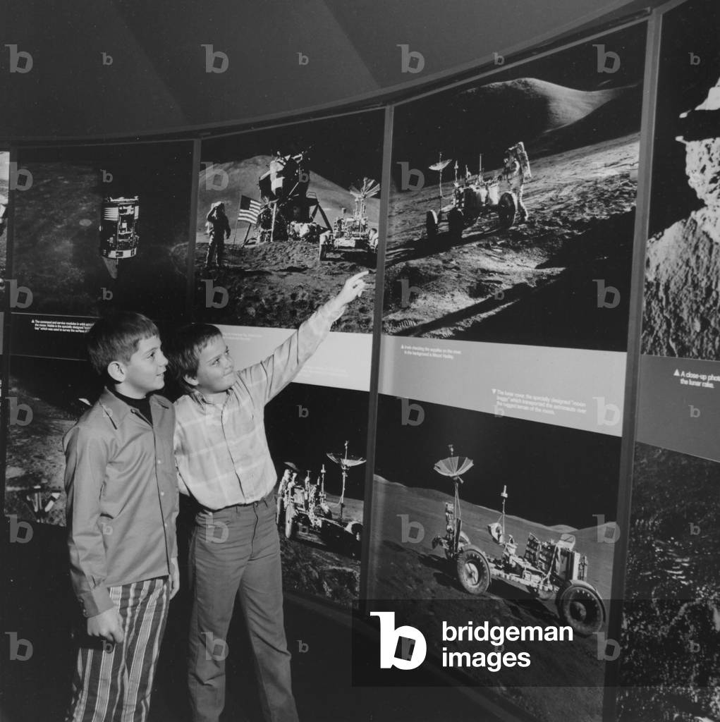 Two Young Boys Looking At Images Of A Moon Landing