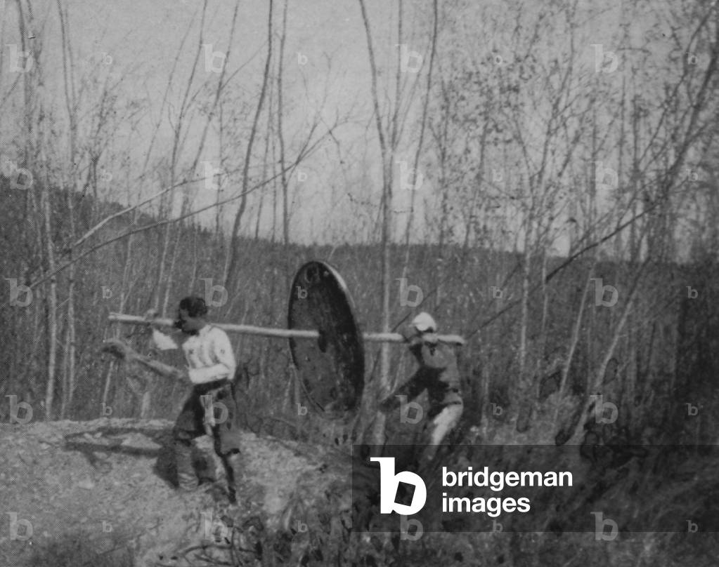 Two Men Carrying A New York Engineering Company Empire Drill In Manchuria