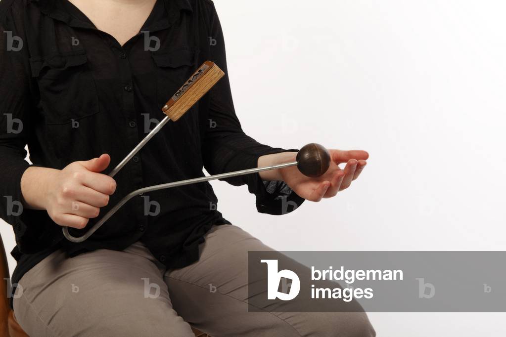 Vibraslap being played. Percussion sound effect instrument played by striking the wooden ball, making the metal teeth inside the wooden box rattle. Modern equivalent of the 'Jawbone of an Ass'