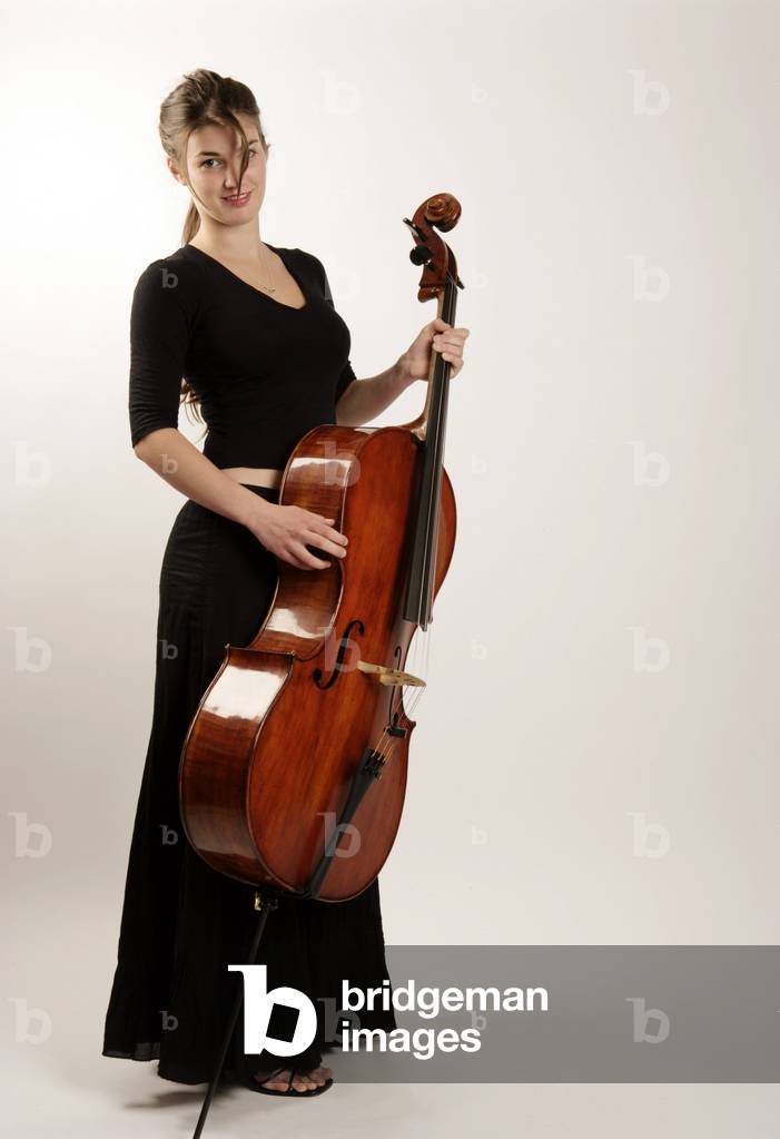 Cello -  young woman in concert dress holding instrument. Cellist.