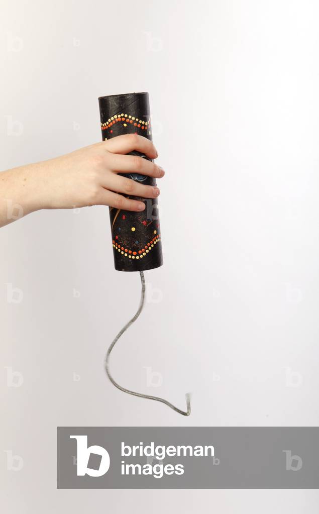 Thunder drum or spring drum being played by a percussionist. Small tube with a single plastic head, with a metal spring hanging down from the centre of the head. Played either by pulling the spring and letting go, or moving the instrument in a circular mo
