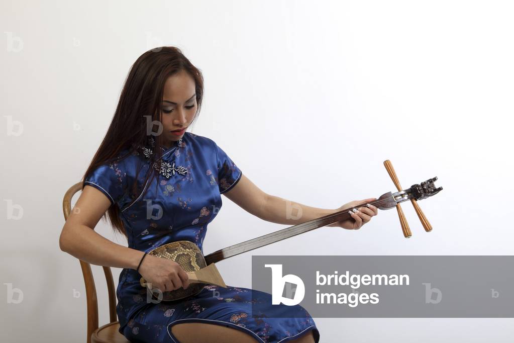 Oriental woman playing a Sanxian or San Hsien, or Hsien Tse. Chinese 3 stringed lute.