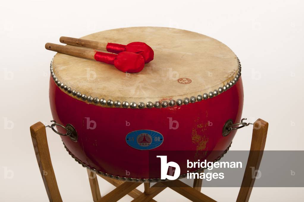 Chinese Tom Tom suspended on a traditional frame stand. Also known as Ku. Double headed Barrel shaped drum, with cloth covered beaters. Heads secured with nails driven into the wooden shell. Generic