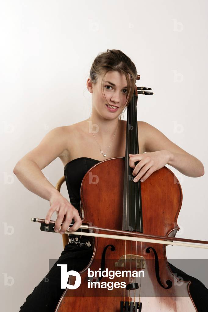 Cello - young woman in concert dress,  playing position. Cellist.