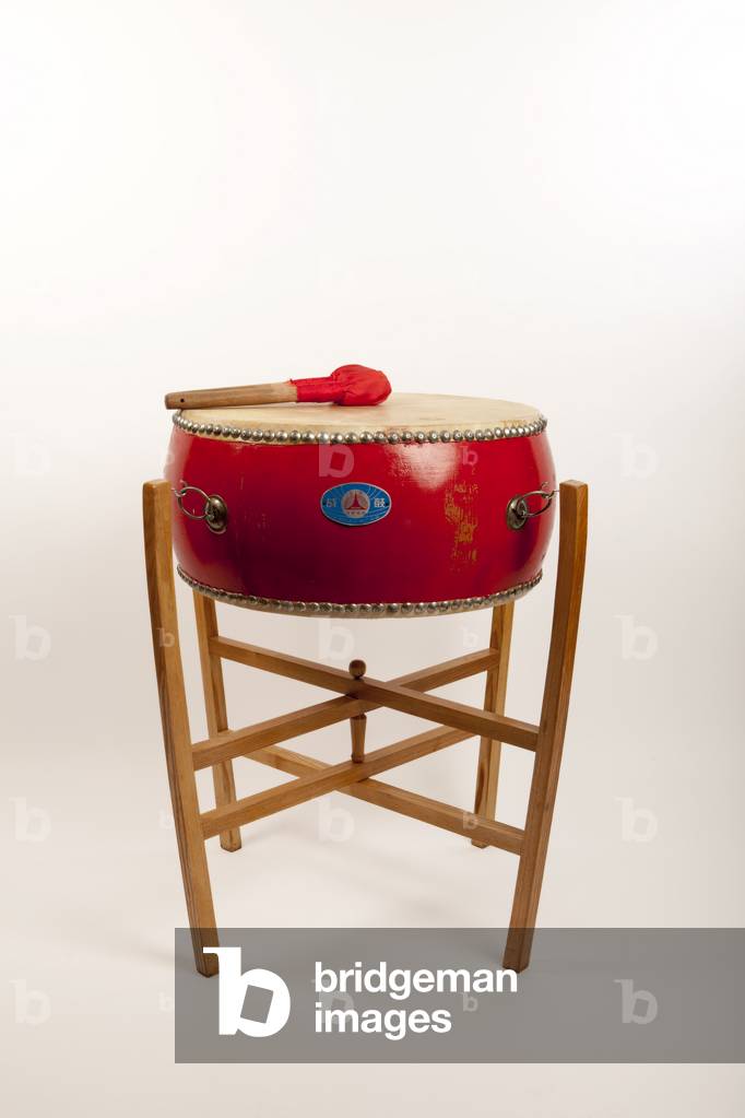 Chinese Tom Tom suspended on a traditional frame stand. Also known as Ku. Double headed Barrel shaped drum, with cloth covered beaters. Heads secured with nails driven into the wooden shell. Generic