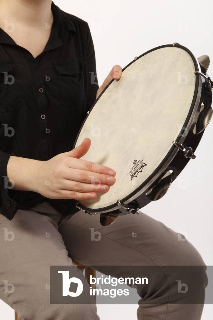 Pandeiro Tambourine in playing position. Held in one hand and played with the thumb and fingers of the other hand. Technique and striking positions.