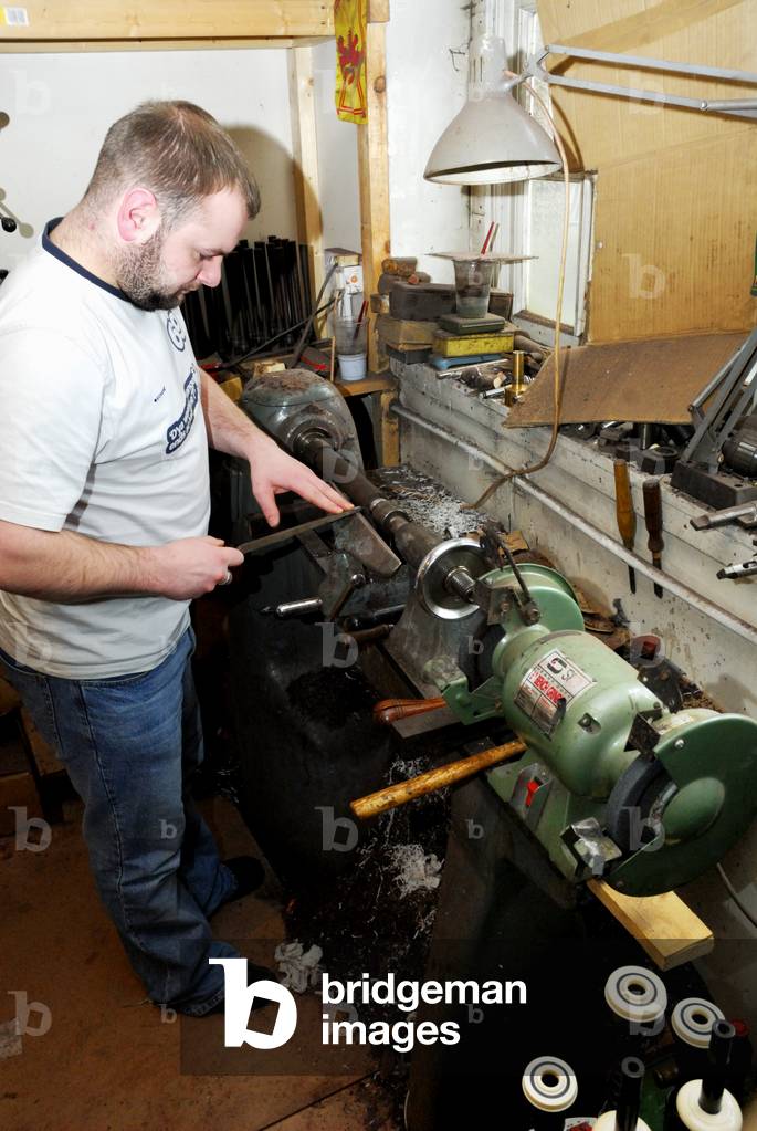 Bagpipe maker turning wooden billet for chanter, on lather
